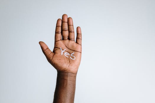 Close-up of a raised hand with 'Yes' written on the palm, symbolizing agreement and positivity.