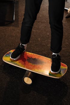 A close-up of a person practicing balance on a colorful training board indoors.